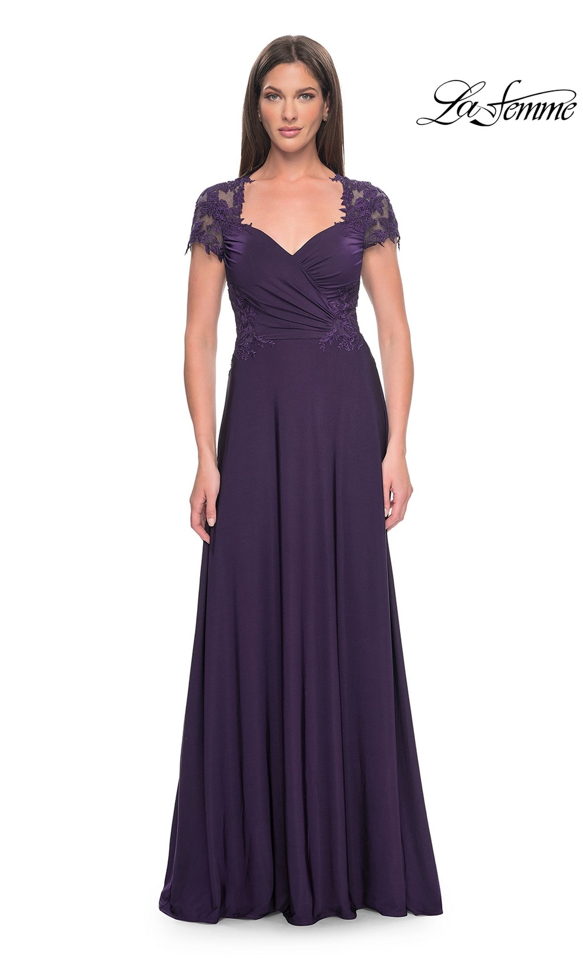 A woman wears the La Femme Cap Sleeve Long Purple Prom Dress 31906, featuring lace cap sleeves, a sweetheart neckline, ruched bodice, and a flowy floor-length skirt. The